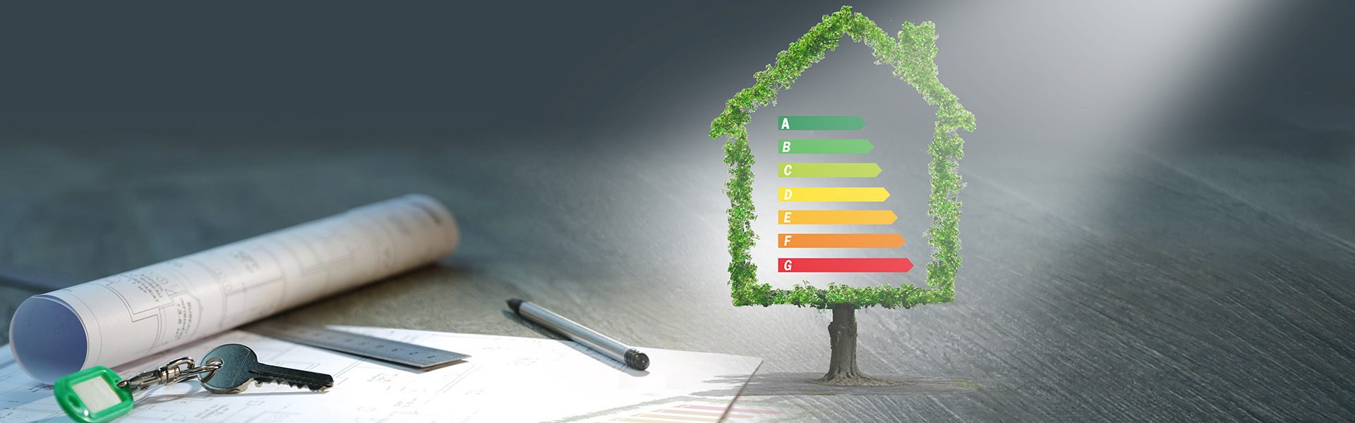 Das Bild zeigt ein Haus-Icon, das aus grüner Vegetation gebildet ist, mit einem Energieeffizienzschema in der Mitte, dargestellt durch Farben von rot bis grün. Neben dem Icon liegen ein Plan, ein Schlüsselbund und ein Bleistift auf einem Tisch, was auf Architektur oder Bauplanung hinweist.